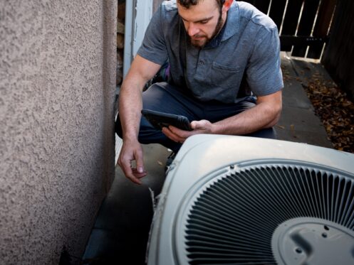 Man with a tablet standing beside an AC unit
